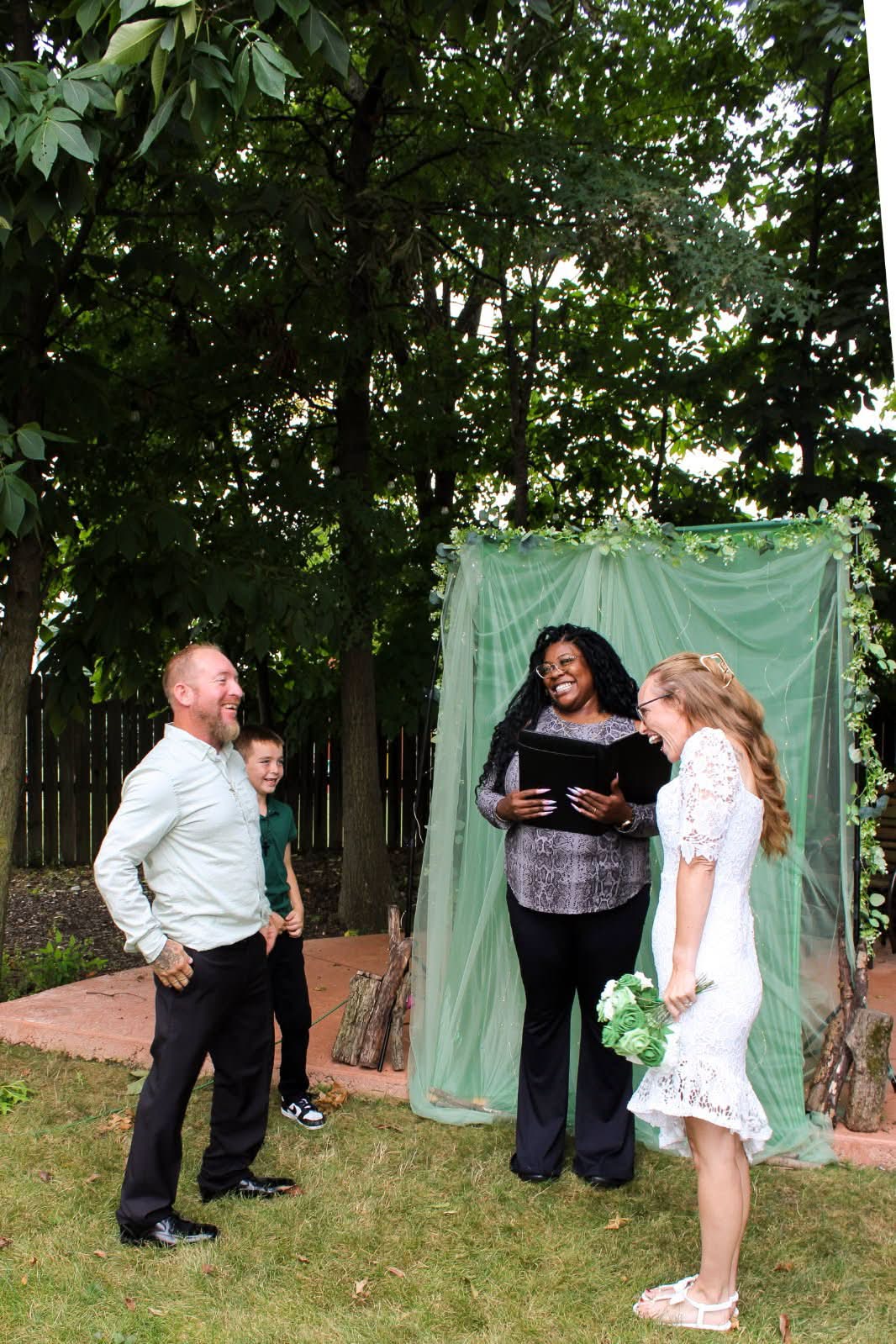 A couple laughing with Angelica at their backyard ceremony
