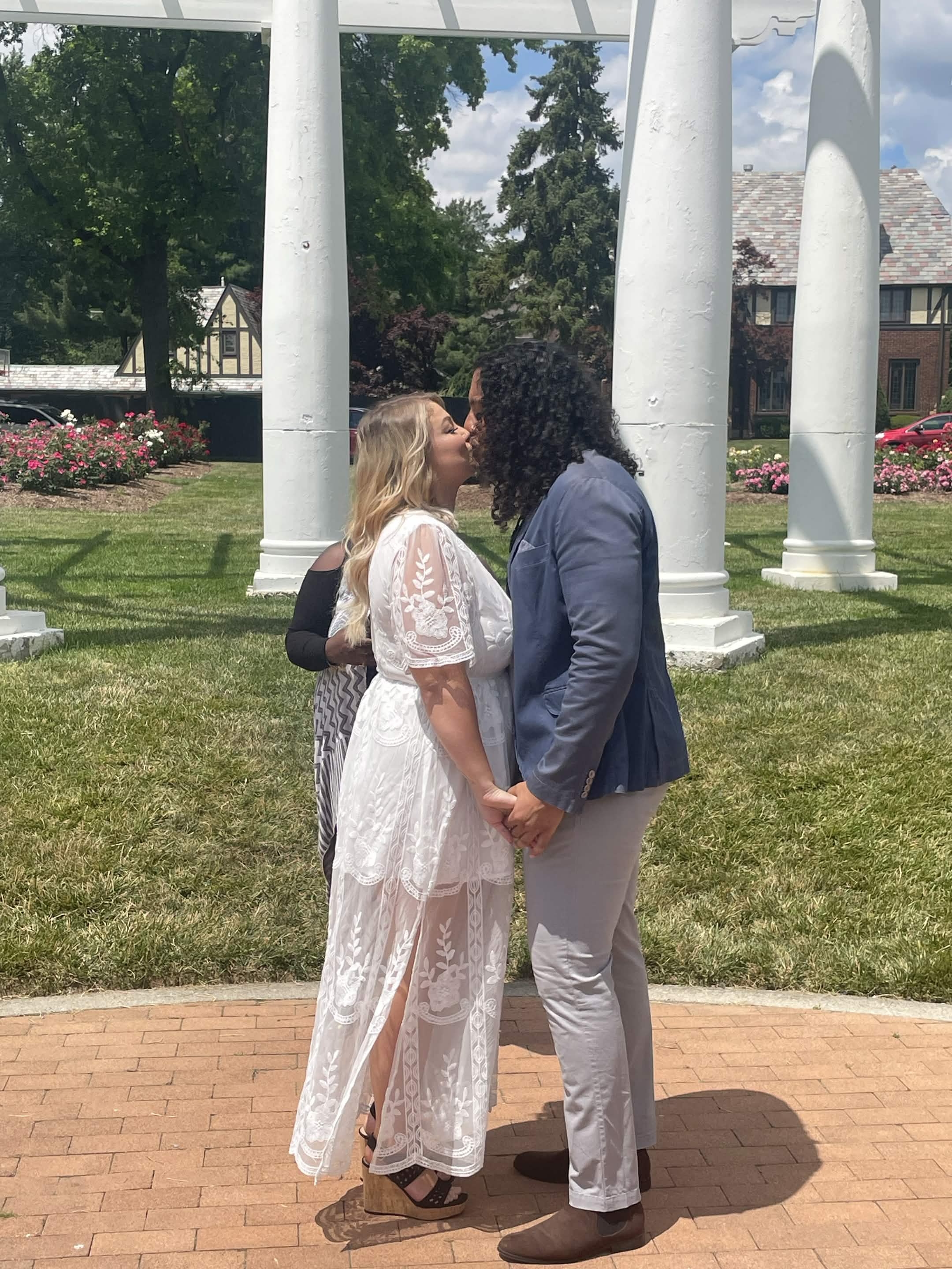 Newlyweds kissing beneath white garden columns