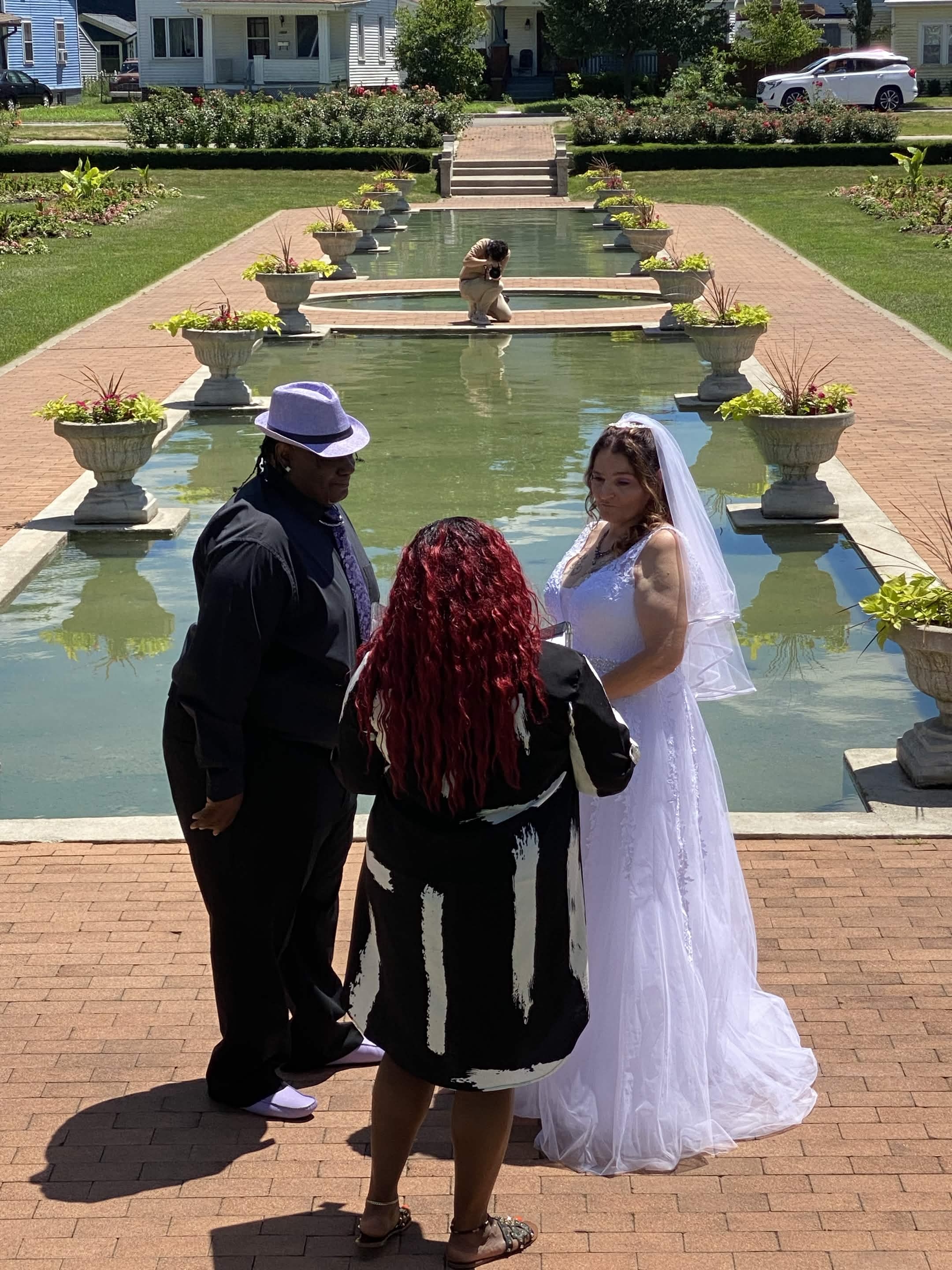 Angelica officiating a garden ceremony beside a reflecting pool